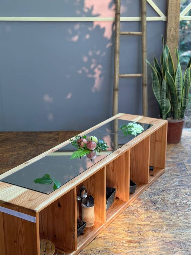 Wooden shelf topped with a mirror, arranged with passion fruit, ferns and leaves